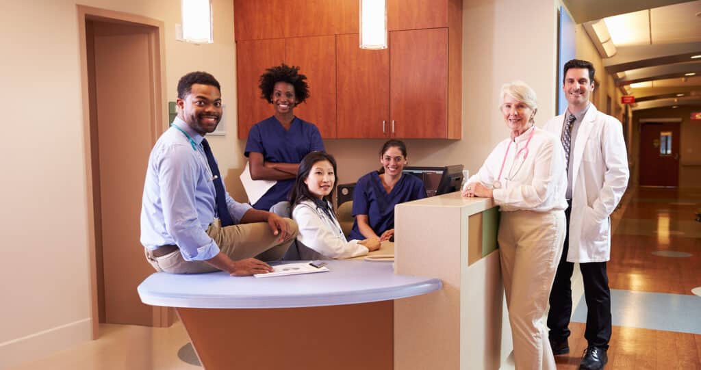 Portrait Of Medical Staff At Nurse's Station In Hospital