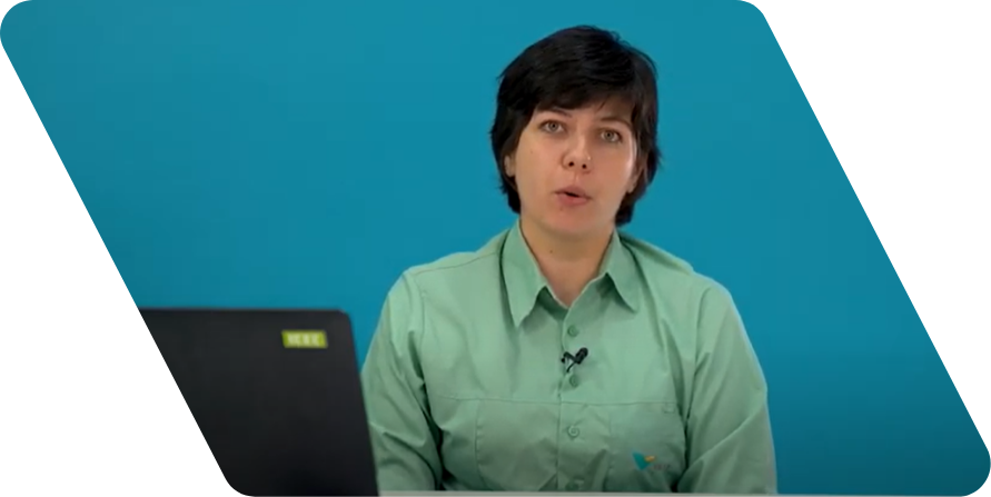 Mulher branca de cabelos lisos pretos e curtos olhando para a câmera. Ele usa uma camisa de cor verde clara e está na frente de uma parede azul.