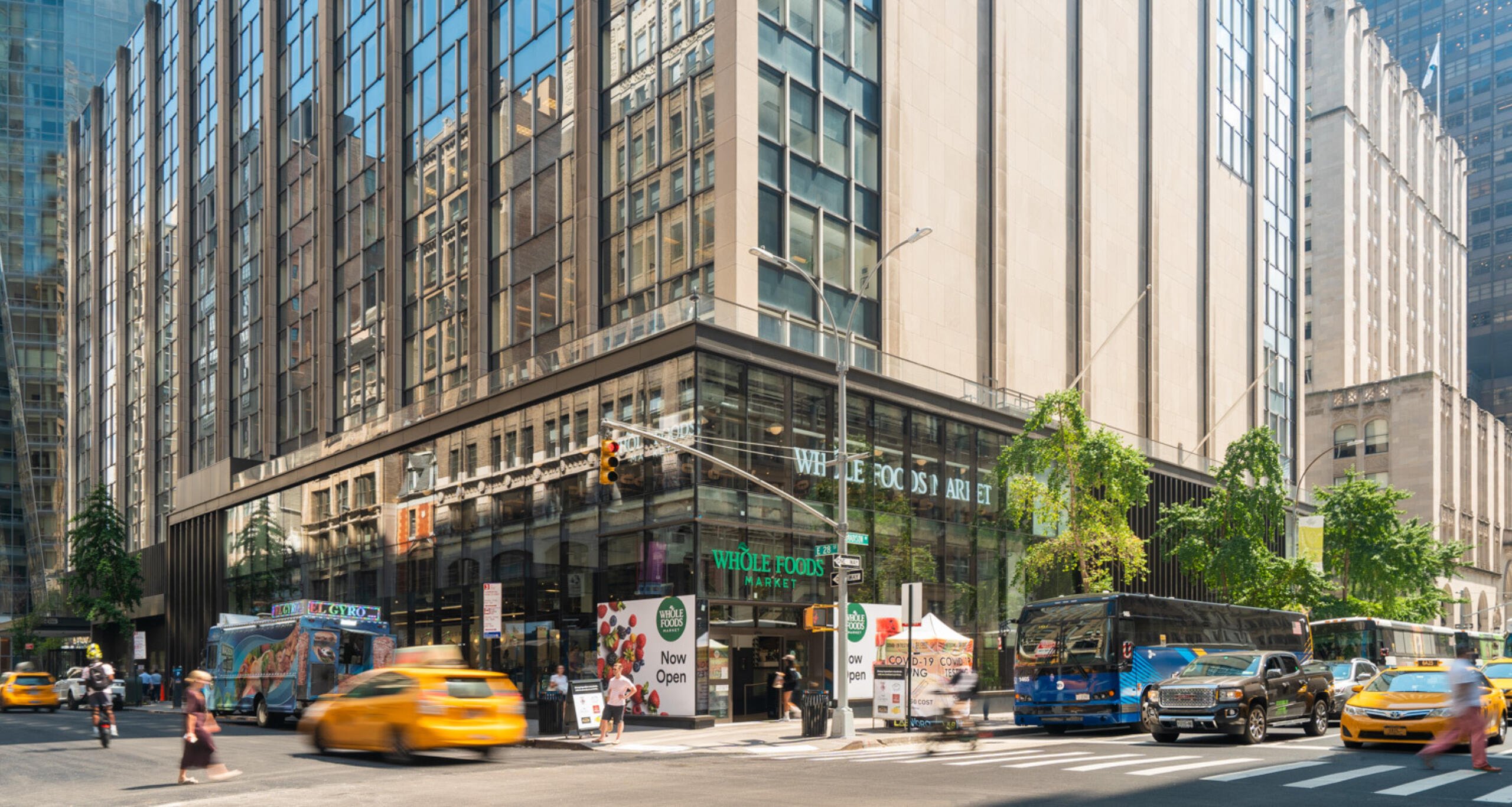 Exterior view of 63 Madison façade with cars and pedestrians in foreground