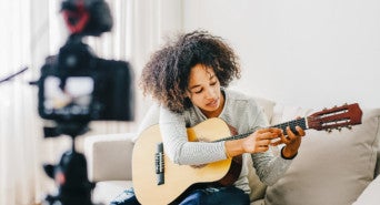 Eine junge Frau streamt eine Gitarrenstunde