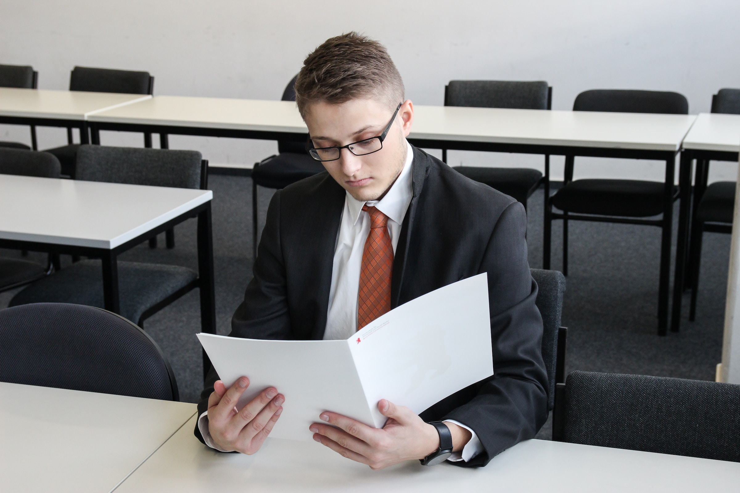 Guy Reading a paper packet writing a resume