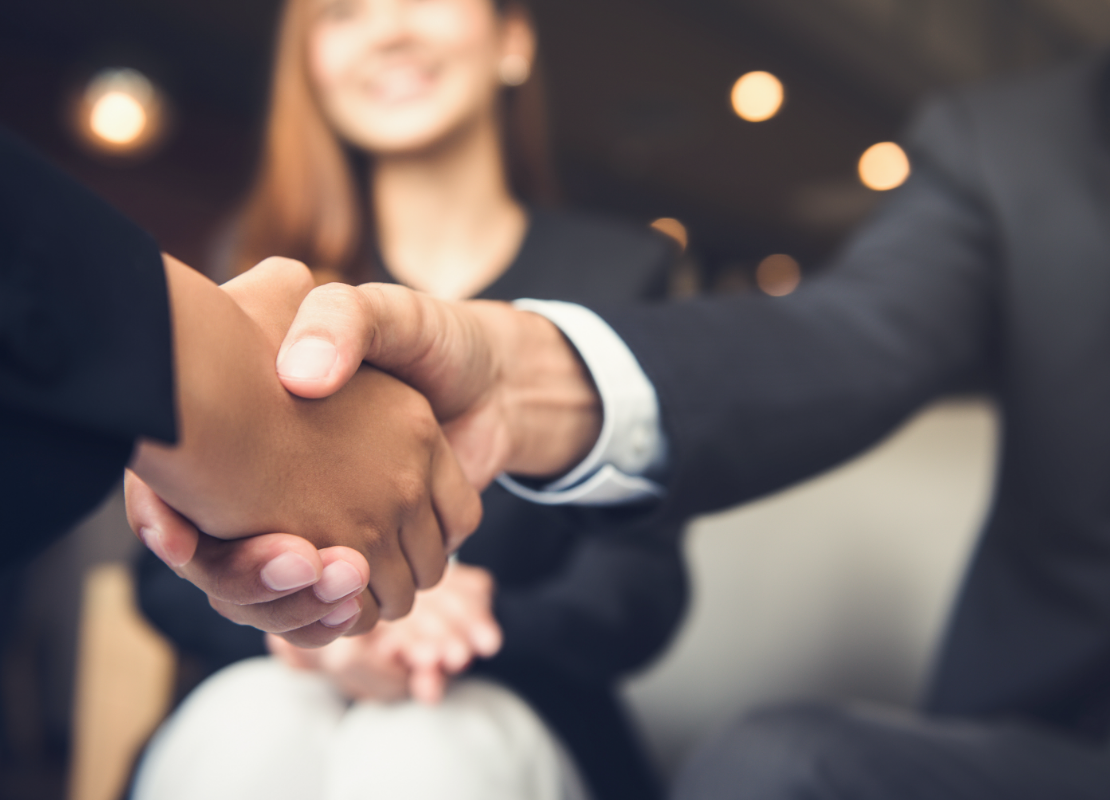 two people shaking hands with woman in the background