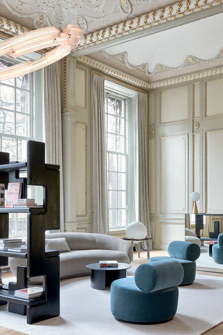 The opulent interior of the KARL LAGERFELD headquarters in the heart of Amsterdam, with full-height windows, gilded ceilings, ornate wall panelings, and soft plush furnishings.   ​