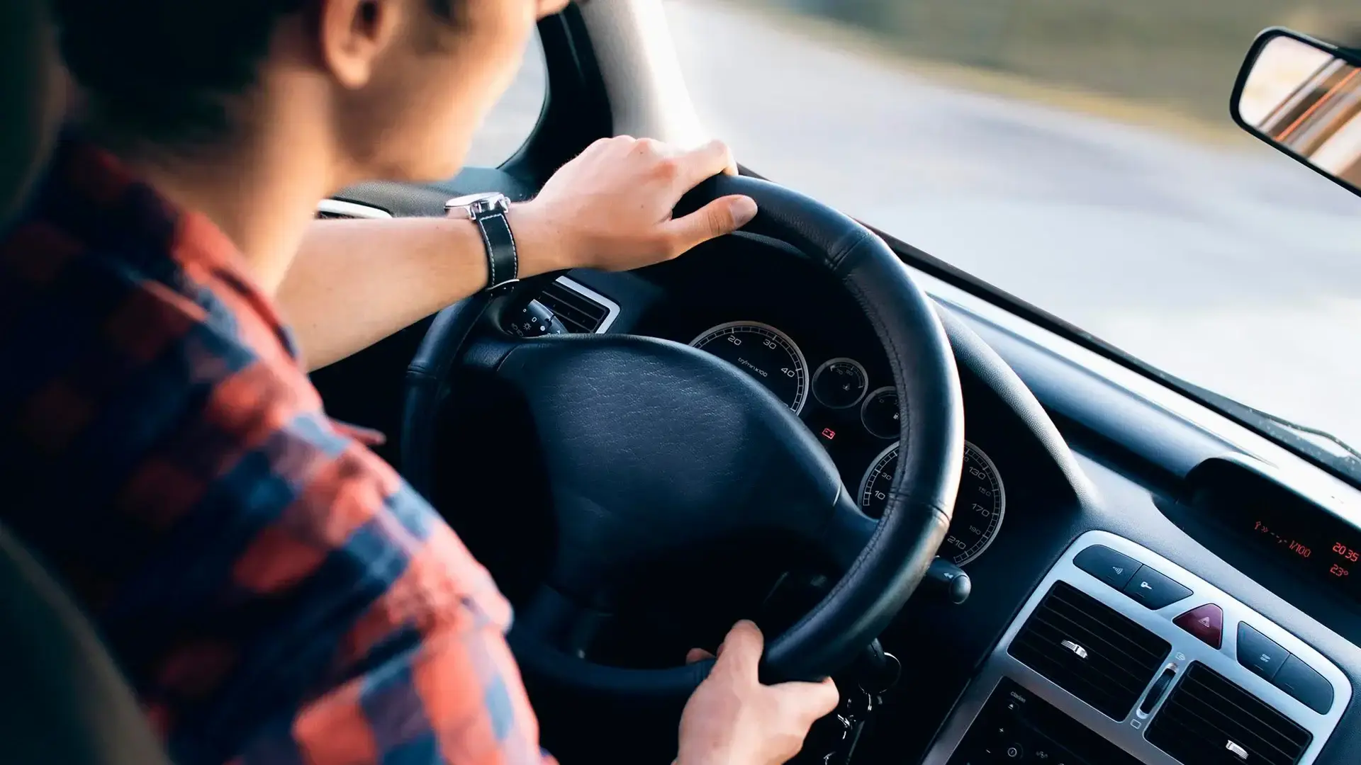 Visão traseira de um motorista com as mãos no volante do carro