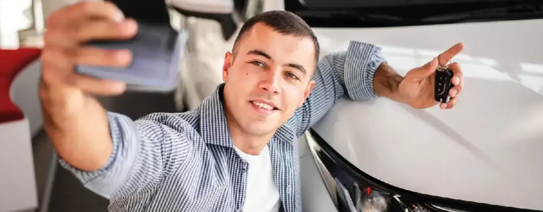 Homem sorrindo em comemoração com a chave do carro na mão