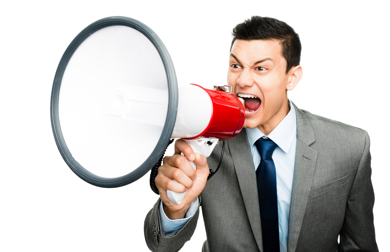 Shot of an asian businessman shouting into a megaphone against a studio background