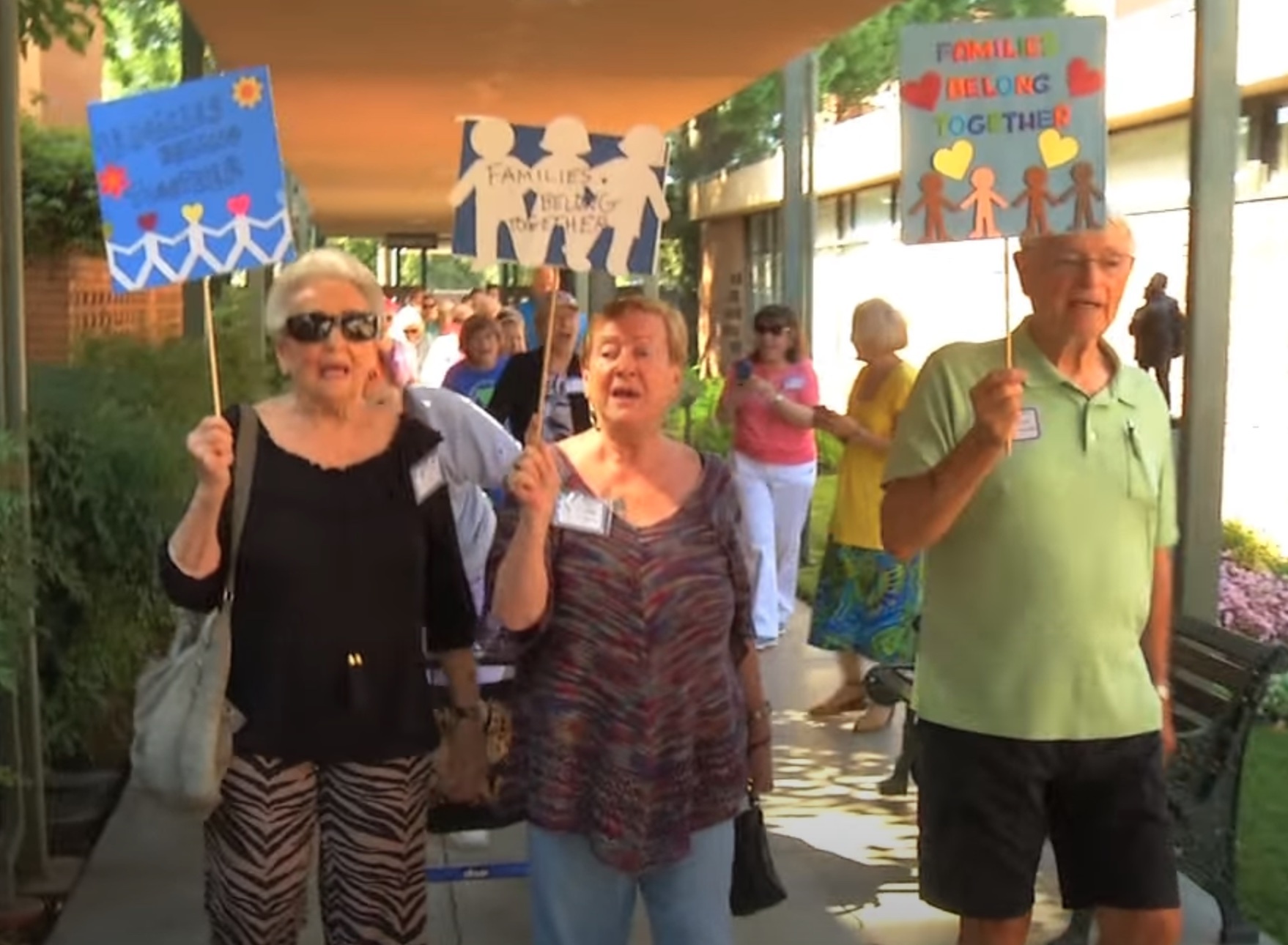 Two women and a man marching with signs