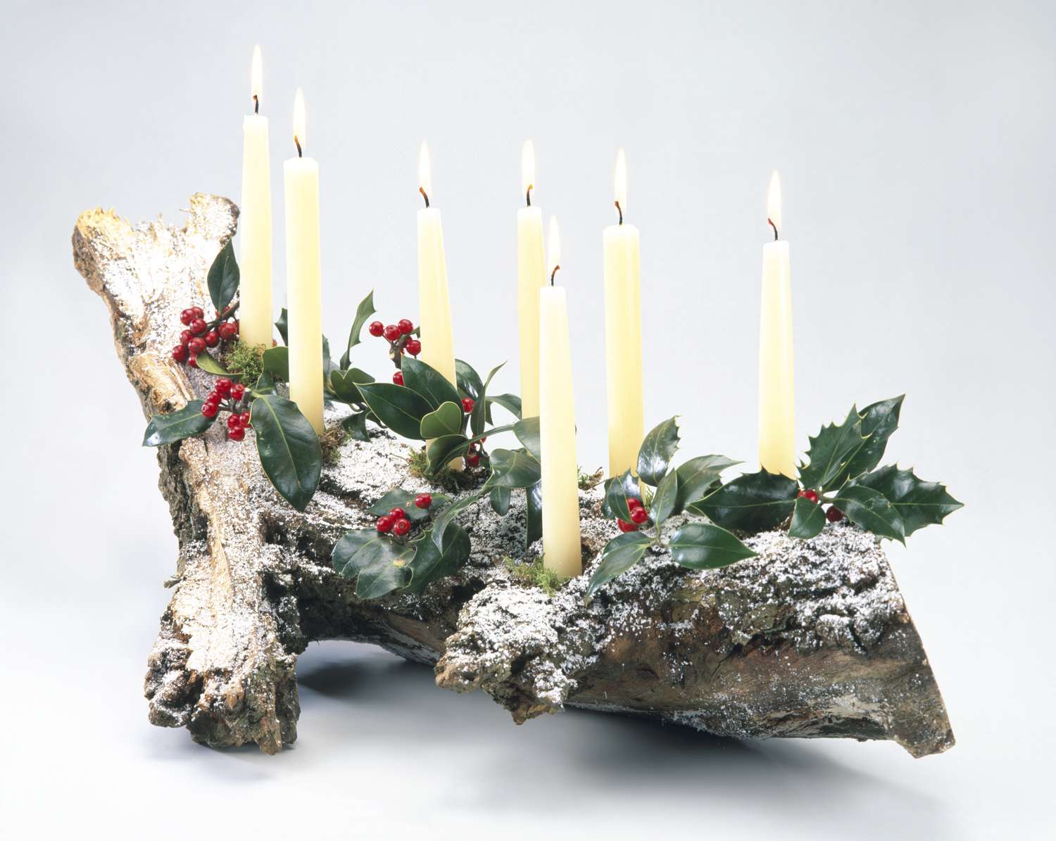 Yule log decorated with candles, holly leaves and berries