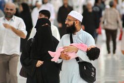 A young Muslim couple and their toddler at Masjid al-Haram, Makkah, Saudi Arabia.