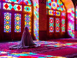 Worshipper in front of stained glass windows of Prayer Hall, Nasir-al Molk Mosque, Shiraz, Iran