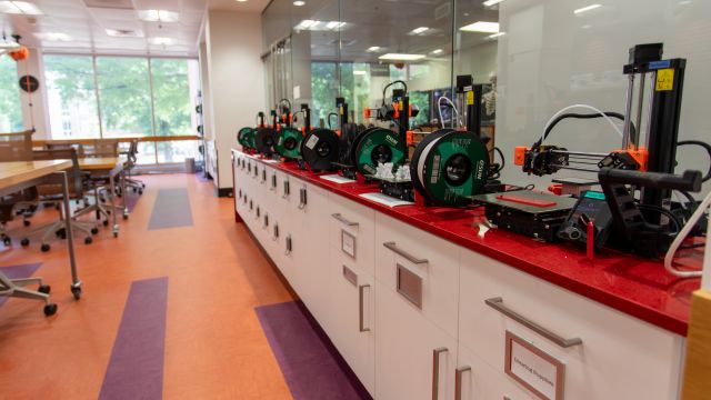 A row of 3D printers on a credenza