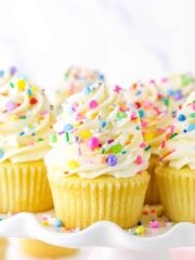 Close up of vanilla cupcakes with vanilla frosting and rainbow sprinkles