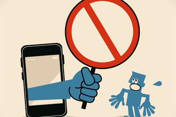 Business person standing in front of a big smartphone, a big hand from the mobile phone holding an empty prohibition sign