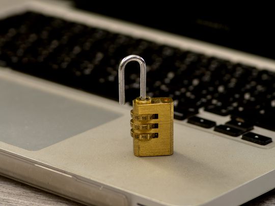 A golden padlock unlocked on a laptop.