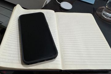 Dead iPhone 14 Pro Max lying on a notebook on a desk.