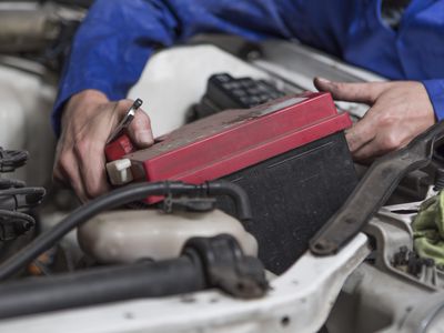 Mechanic working on car removing battery