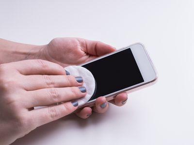 Hands using soft cotton makeup pad on a dark touch screen