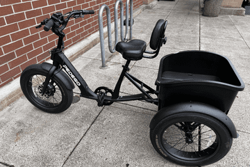 The Pedego Fat Tire Trike parked next to a bike rack