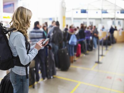 Tourist texting at airport check-in desk