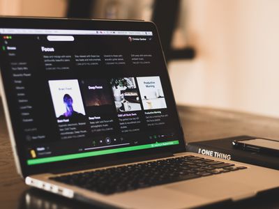 Computer sitting on table showcasing Spotify