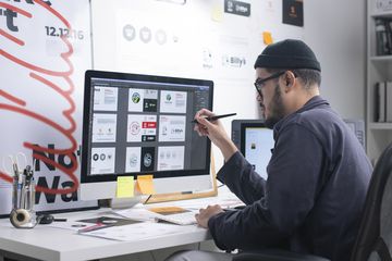 An artist working at a computer in a home office.