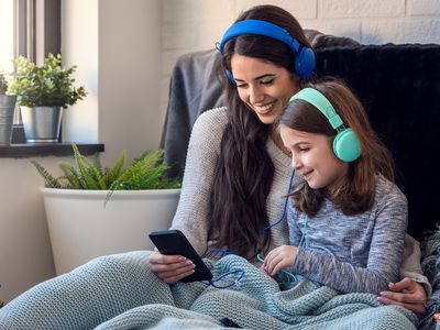 A woman and her daughter wearing headphones and listening to music on an Apple iPhone.