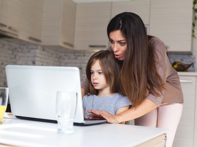 Cute girl and mother using laptop at home