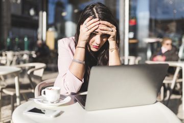 Frustrated businessperson using laptop at an outdoor cafe