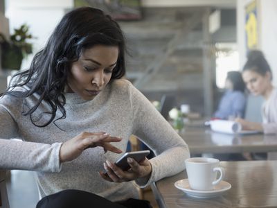 Person using smart phone, drinking coffee in cafe