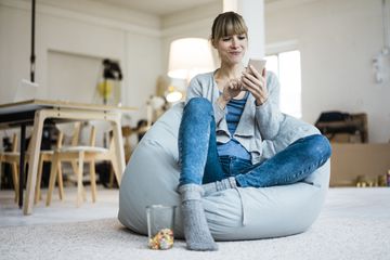 Woman sitting in beanbag chair using cell phone.