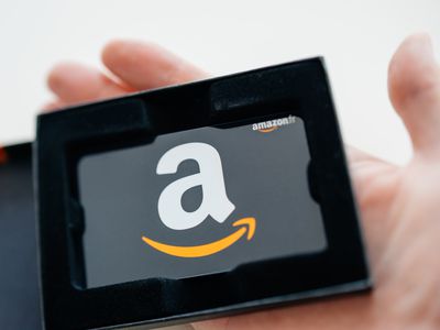 A hand holds an Amazon gift card in a black case