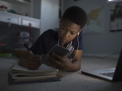 An image of a child looking at his smartphone while studying.