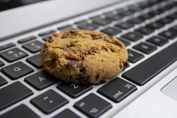 chocolate chip cookie resting on a MacBook keyboard