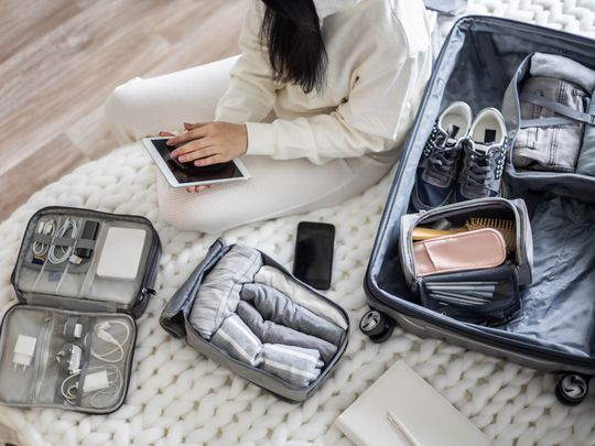 A woman packing gadgets and tech for a flight.