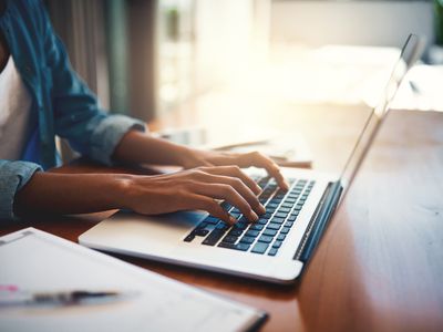 A woman sitting at a desk using a MacBook laptop.