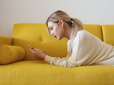 A woman lying on a sofa looking at her smartphone