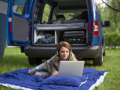 woman using car power to charge laptop on camping trip