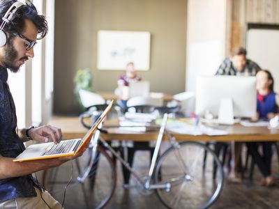 Person listening to music on laptop with bike in the background