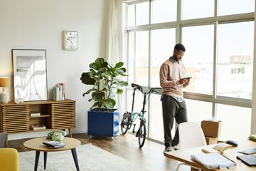 A man standing in a living room looking at his smartphone.