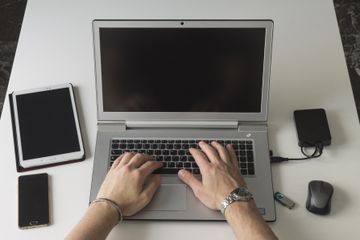 Man using laptop with external hard drive at table