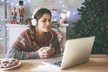 Person with long side pony tail and orange nails wearing headphones and listening to Christmas music