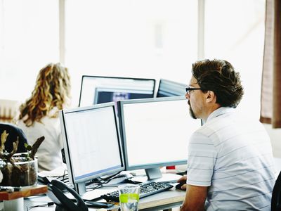 Picture of a business man working on a dual-monitor setup computer in an office