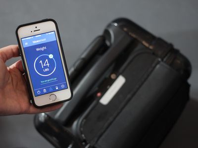 Hand holding a smartphone with luggage in the background