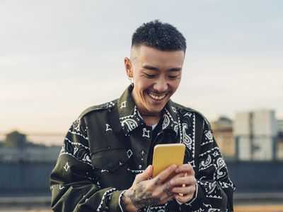 A man with tattoos smiling at his phone