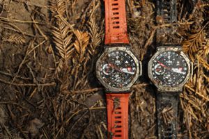 Two Amazfit T-Rex 3 smartwatches against a muddy background of pine needles.