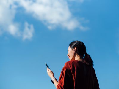 A woman looking at her phone with blue sky in the background