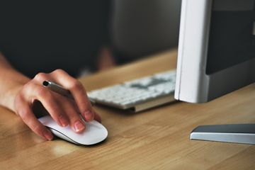 Person holding mouse using desktop computer