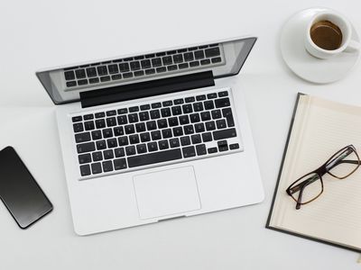 Photo of a Macbook, iPhone and notebook on a desk