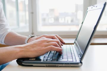 A man using laptop keyboard wearing a watch