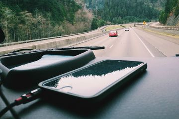 An iPod on a car dashboard connected to an amp with no head unit.